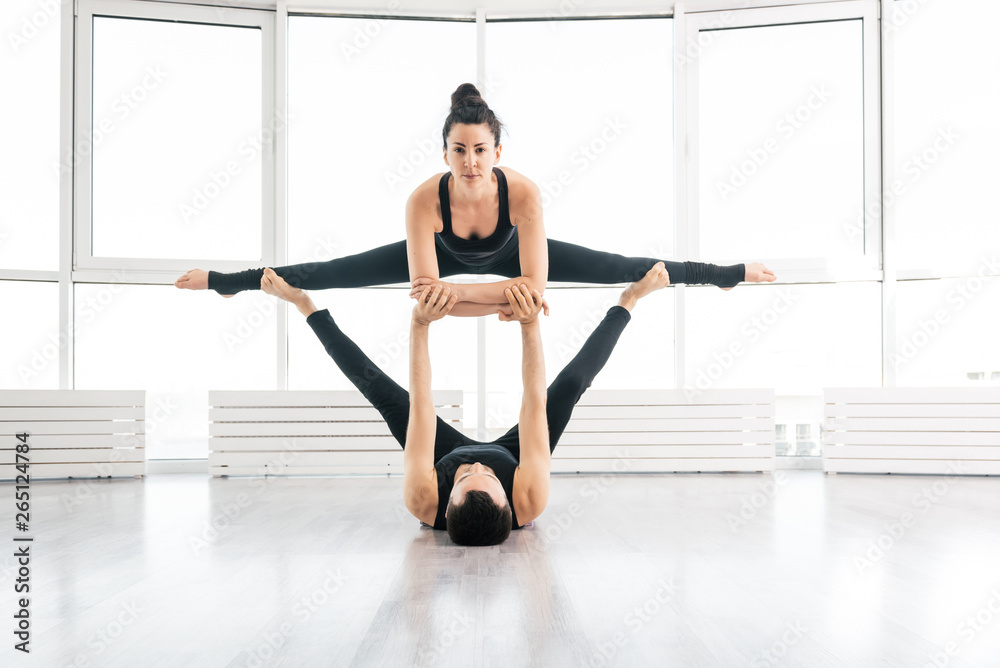 Positive woman practice acro yoga with man partner at studio Positive woman practice acro yoga with man partner at studio