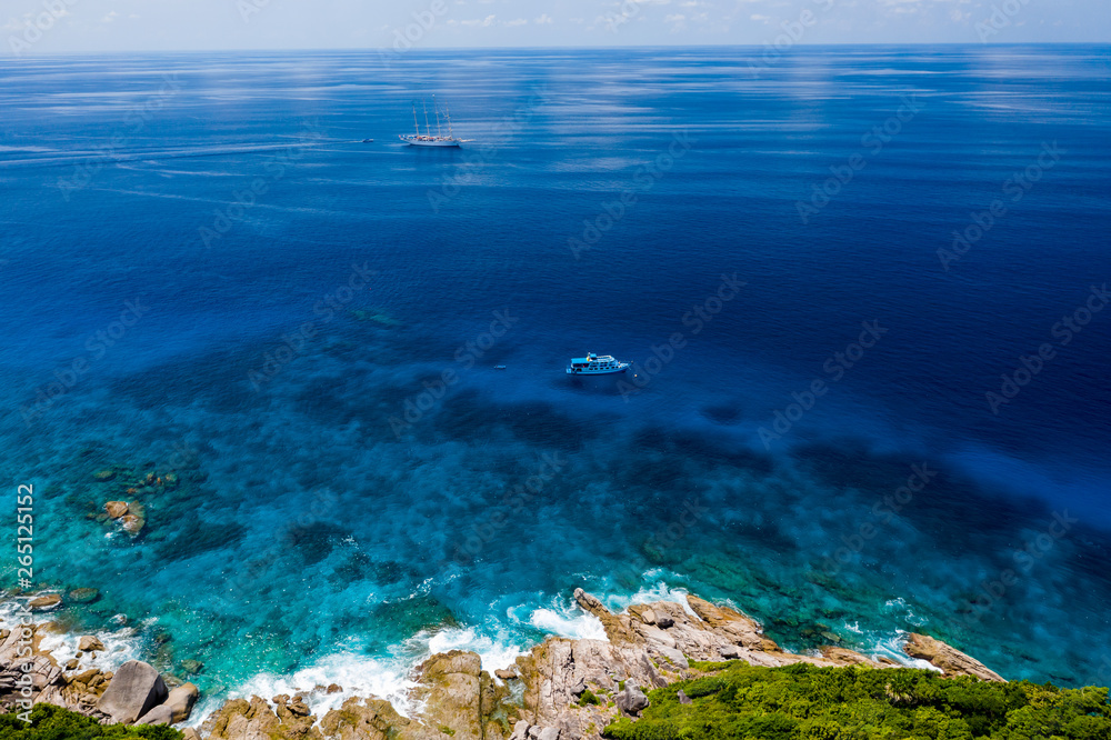 Aerial drone view of boats around the shallow coral reef surrounding beautiful tropical islands (Similan Islands) Aerial drone view of boats around the shallow coral reef surrounding beautiful tropical islands (Similan Islands)