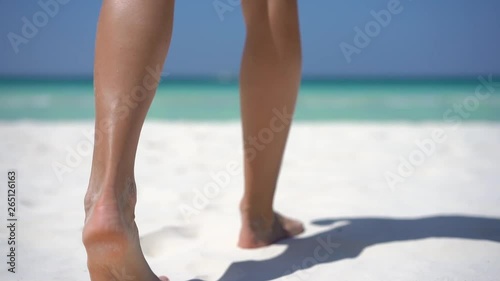 Woman legs closeup walking on the beach sand.