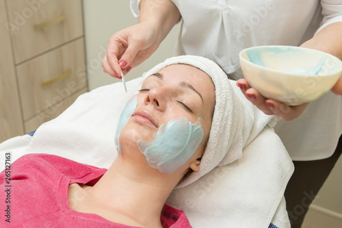 Face skin care. Beautician applying beauty oil mask on face using brush In spa salon	