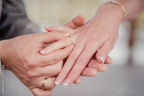 At the wedding, the bride and groom help each other by putting the wedding rings on the ring finger. Close-up.