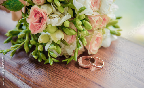 Delicate wedding bouquet with rings on a wooden base. Close-up.