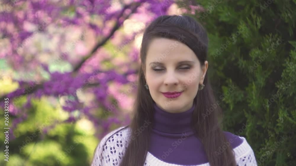 Attractive European girl young woman with long brown hair brunette in white purple clothes in the Park in white sunglasses sends a kiss and heart and smiles, close-up portrait, slow motion Attractive European girl young woman with long brown hair brunette in white purple clothes in the Park in white sunglasses sends a kiss and heart and smiles, close-up portrait, slow motion