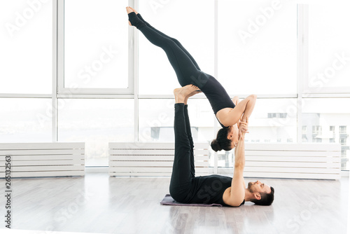 Positive woman practice acro yoga with man partner at studio