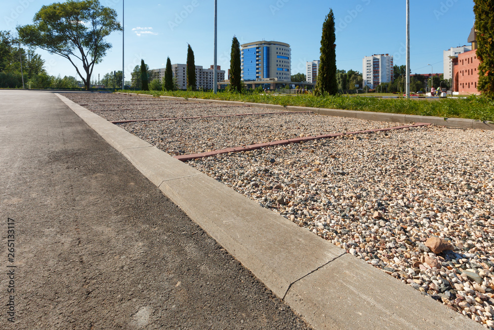Eco-friendly parking with gravel is separated from the asphalt road by ...