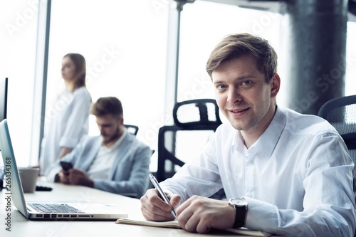 Portrait of young man sitting at his desk in the office.