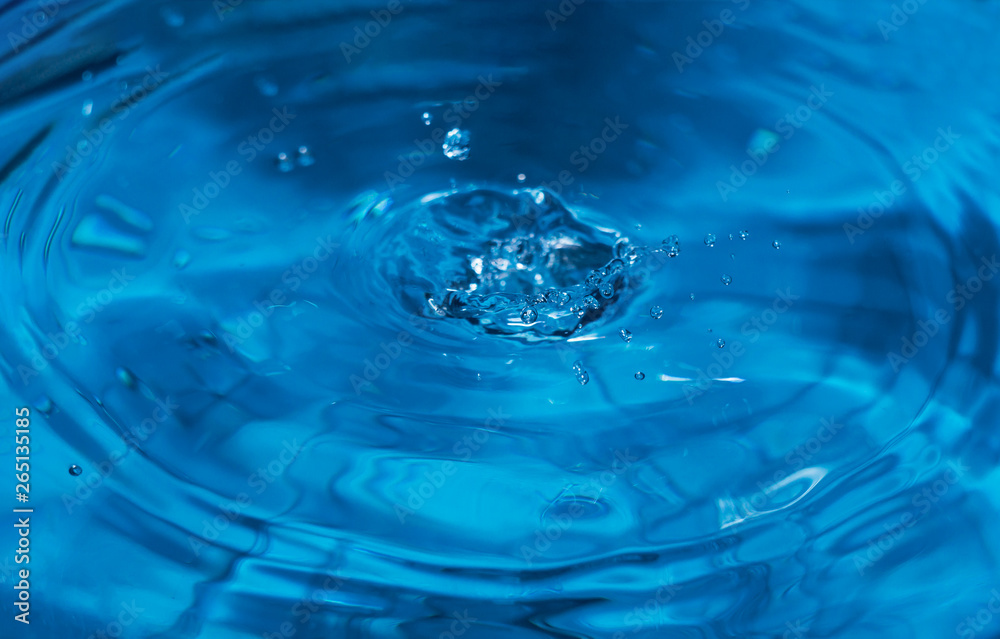 Splashes from a drop of water. Rain drops on a blue background. The texture of the water. Aqua, ripple, turquoise, macro
