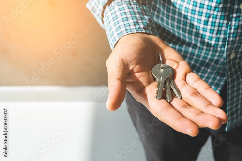 Close up hand holding key in house.