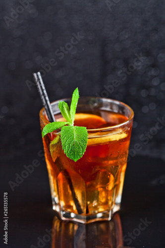Traditional fresh iced tea with lemon, mint leaves and ice cubes in glass.