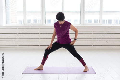 Healthy lifestyle, people and sport concept - Middle aged woman doing yoga