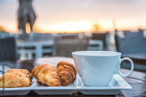 Breakfast with croissants on the sea beach terrace and sunrise photo