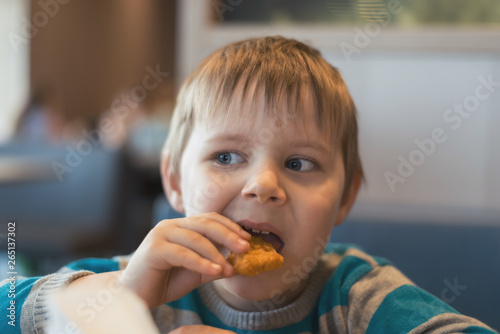 The little boy eats in a fast food restaurant.