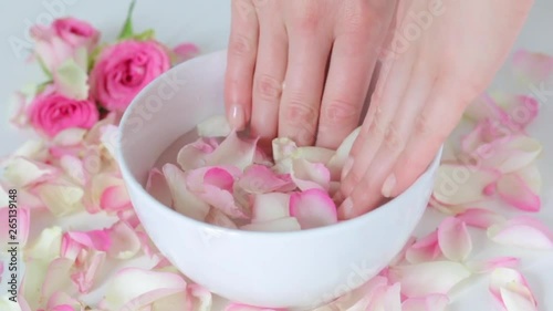 girl throws rose petals in a container with water and lowers her fingers