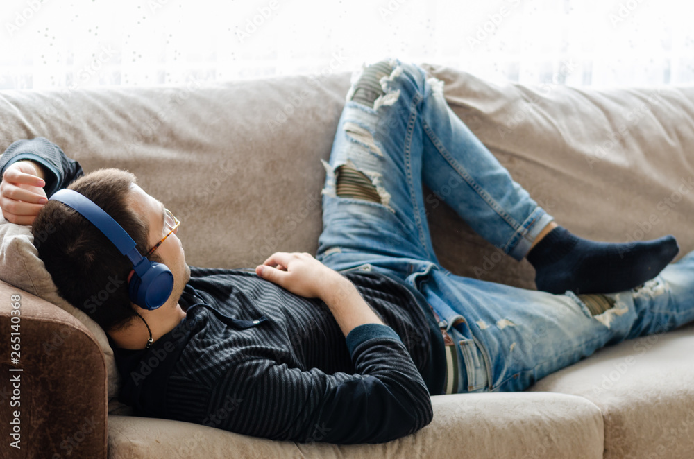 Young man is listening to music at home - obrazy, fototapety, plakaty 