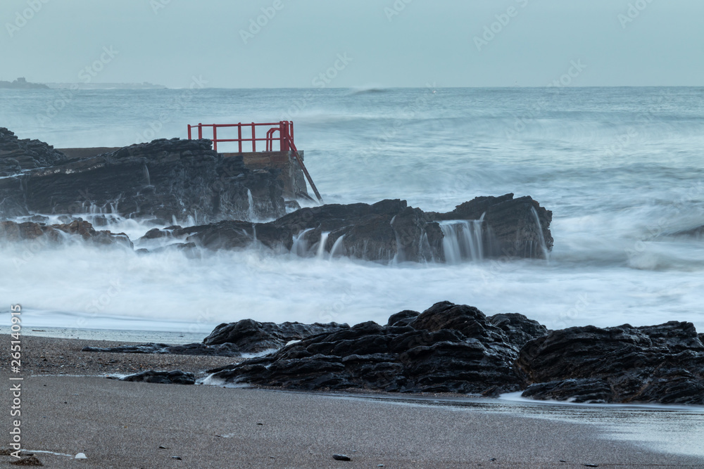Stormy seas, waves crashes against rocks.