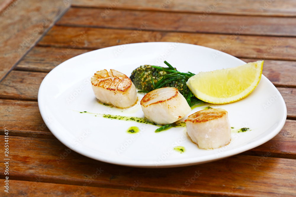 Portion of grilled scallops on plate on table Portion of grilled scallops on plate on table
