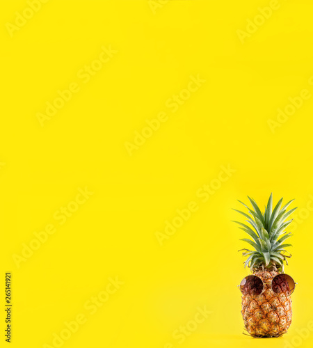 Creative pineapple looking up with sunglasses and shell isolated on yellow background, summer vacation beach idea design pattern, copy space close up