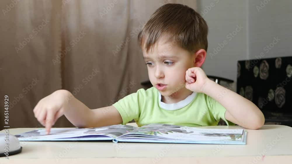 A child reads a book while sitting at the table at home A child reads a book while sitting at the table at home