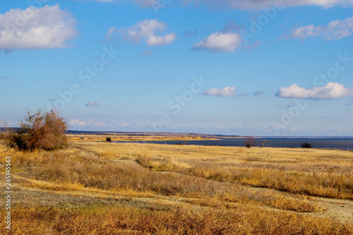 The nature of the earth. Steppe  field and road. Deserted shore  cliff on the banks of the river. Trees Autumn. Cool. Daytime. blue sky with clouds