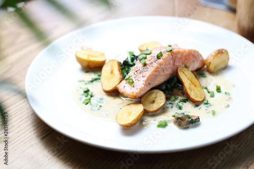 Salmon fillet with baked potatoes on a cream sauce with chives
