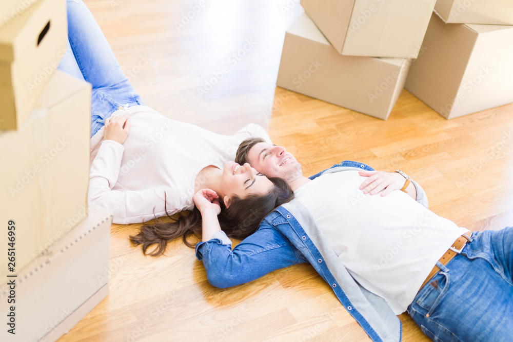 Young beautiful couple relaxing lying on the floor around cardboard boxes at home, smiling happy moving to a new house Young beautiful couple relaxing lying on the floor around cardboard boxes at home, smiling happy moving to a new house