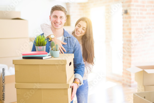 Beautiful young couple smiling in love holding cardboard boxes, happy for moving to a new home