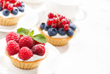 mini tarts with cream and berries on white background