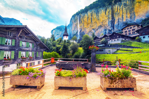 The picturesque landscape with flowers, a waterfall and canyon church in Lauterbrunnen in the Swiss Alps, Switzerland, Europe