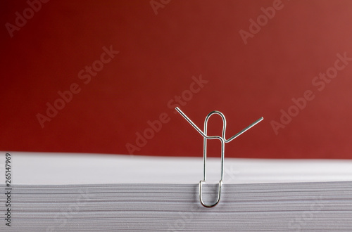 Paper Clip with Hands Aloft on White Paper on Red Background