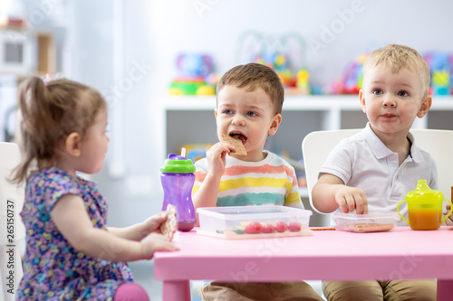 Group of children eating healthy food in daycare centre