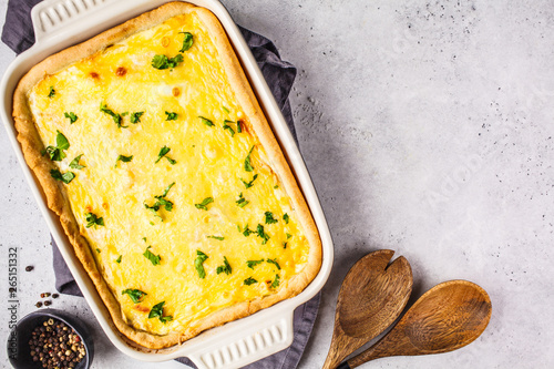 Quiche with cheese and greens in a black baking dish.