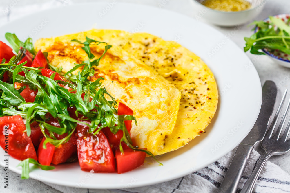 Classic omelet with cheese and tomatoes salad on white plate.