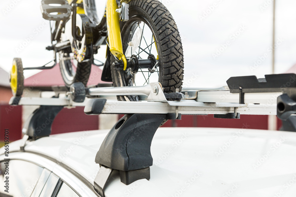 Bicycle transport - a children's bicycle on the roof of a car against the sky in a special mount for cycling. The decision to transport large loads and travel by car