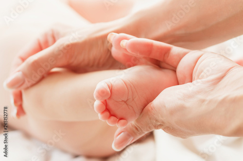 Hands of woman and baby feet, soft focus background © lisssbetha