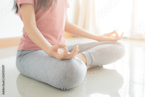 Close up hand and half body of healthy woman sit in lotus Yoga position.Young healthy woman sitting posture exercise in home.Concept of meditating,lifestyle and relaxation. photo