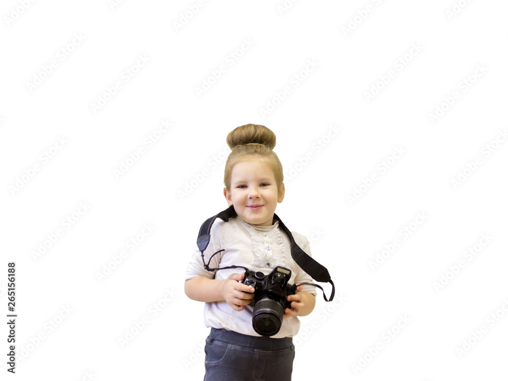 A little girl in business clothes holds a reflex camera in her hands in front of her face. The child wants to take a picture. The baby learns to take pictures and studies the complex technique