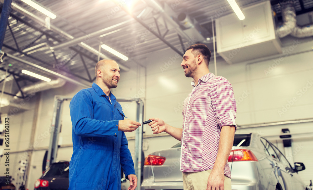 auto service, repair, maintenance and people concept - mechanic with clipboard giving key to happy smiling man or owner at car shop auto service, repair, maintenance and people concept - mechanic with clipboard giving key to happy smiling man or owner at car shop