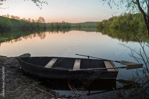 Boat with oars on the river shore at sunset. Selective focus.