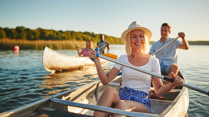 Laughing young woman canoeing with friends on a sunny afternoon