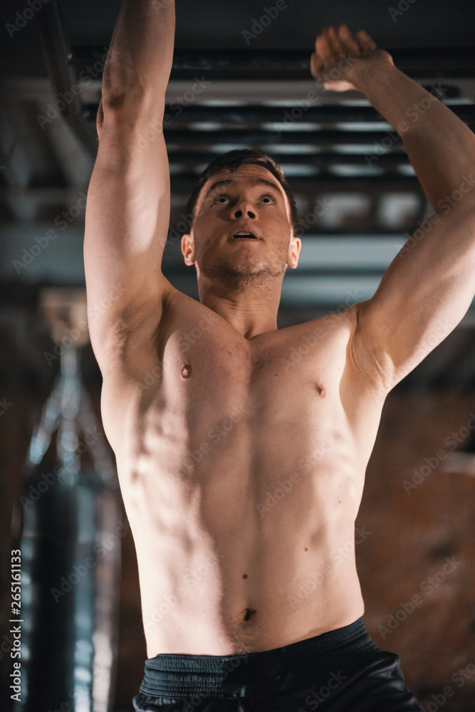 A man in a good shape moving forward on his hands using a ceiling ladder A man in a good shape moving forward on his hands using a ceiling ladder