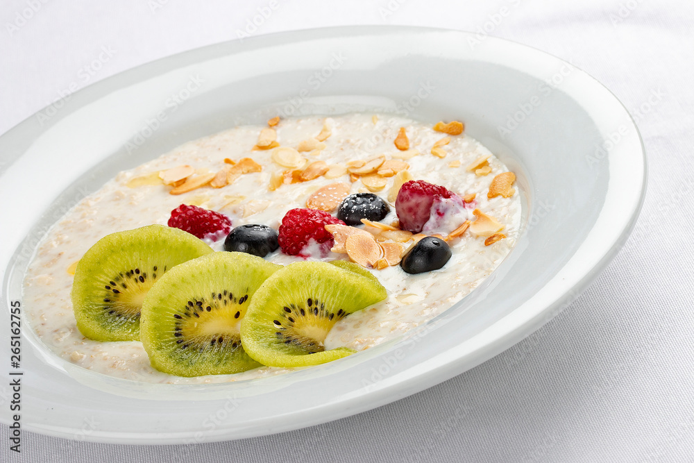 Oatmeal breakfast with berries and kiwi on white background