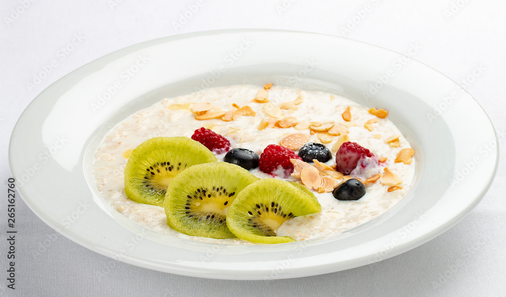 Oatmeal breakfast with berries and kiwi on white background