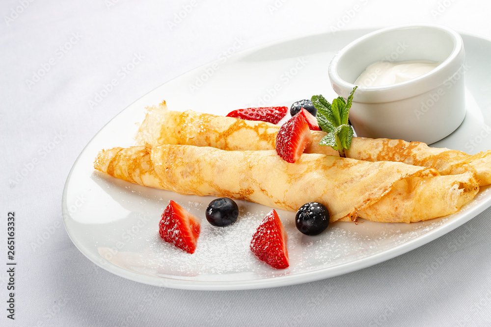 Wheat pancakes with berries and sour cream on white background Wheat pancakes with berries and sour cream on white background