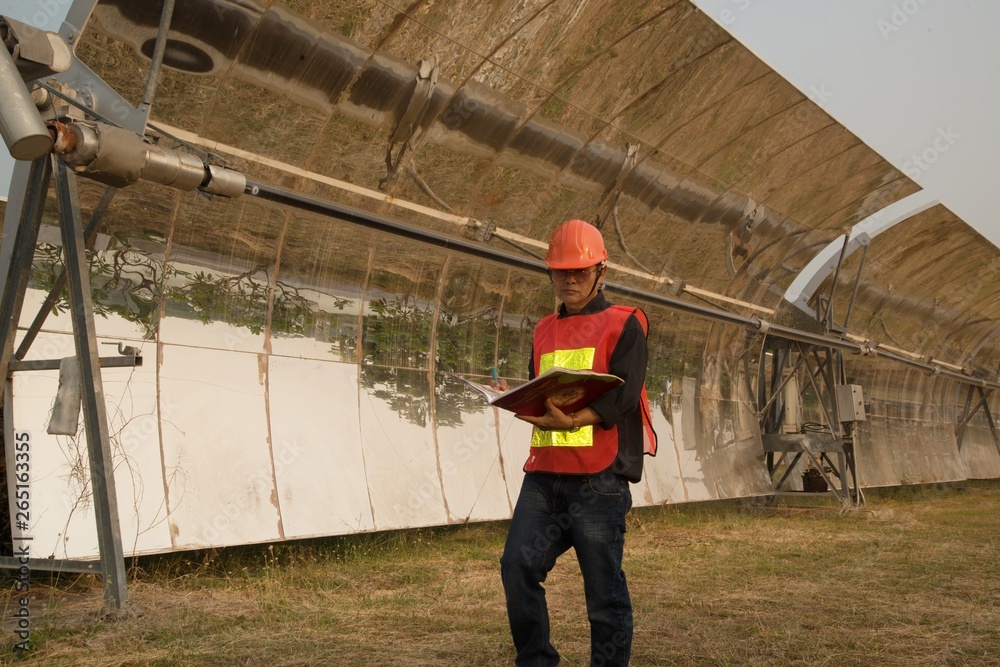 The worker in uniform and helmet checks Solar Parabolic Troughs. The worker in uniform and helmet checks Solar Parabolic Troughs.