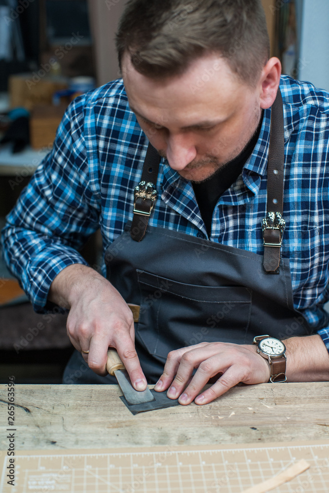 Man working with leather textile at a workshop. Man working with leather textile at a workshop.
