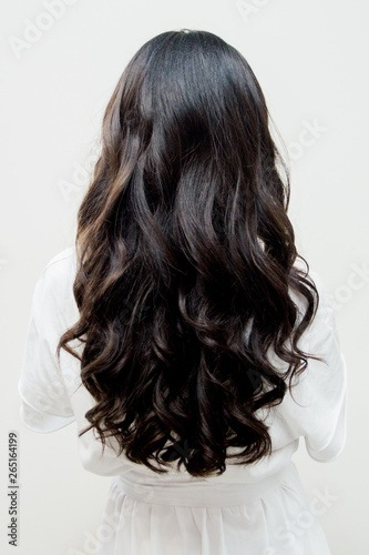 Black long hair of a girl from a back against a white wall
