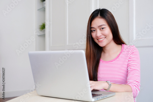 Young asian woman using laptop computer sitting in white room background, people and technology, lifestyles, education, business concept © mangpor2004