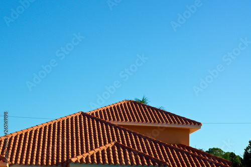 Konstfotografi View of three orange terra cotta clay roof tops against a clear blue sky in bonita springs florida with deep shadows from morning light