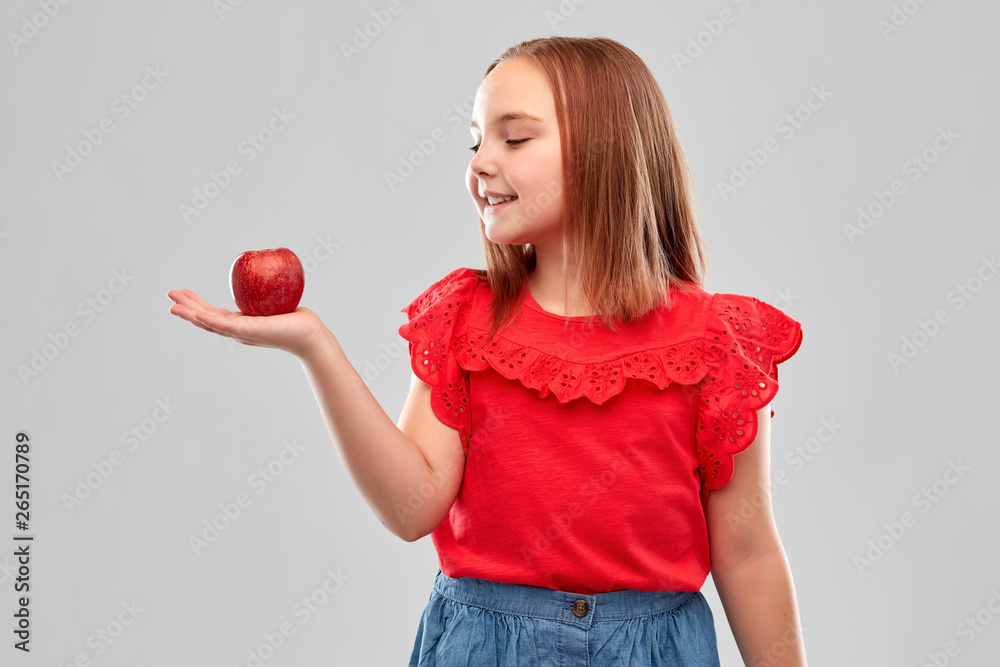 food, diet and childhood concept - beautiful smiling girl holding red apple on palm over grey background food, diet and childhood concept - beautiful smiling girl holding red apple on palm over grey background