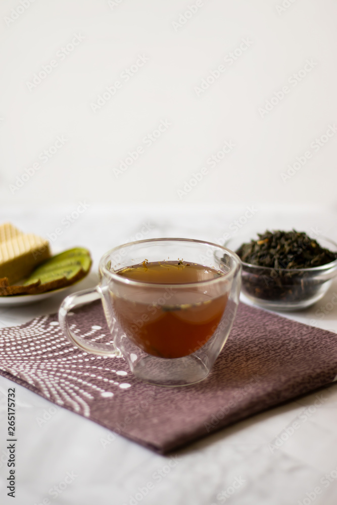 Green tea with jasmine in a transparent mug on a light background. Vertical orientation Green tea with jasmine in a transparent mug on a light background. Vertical orientation